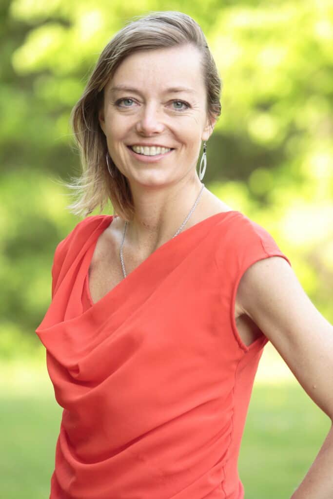 Smiling woman in red dress outdoors for Colorado Precision Medicine.