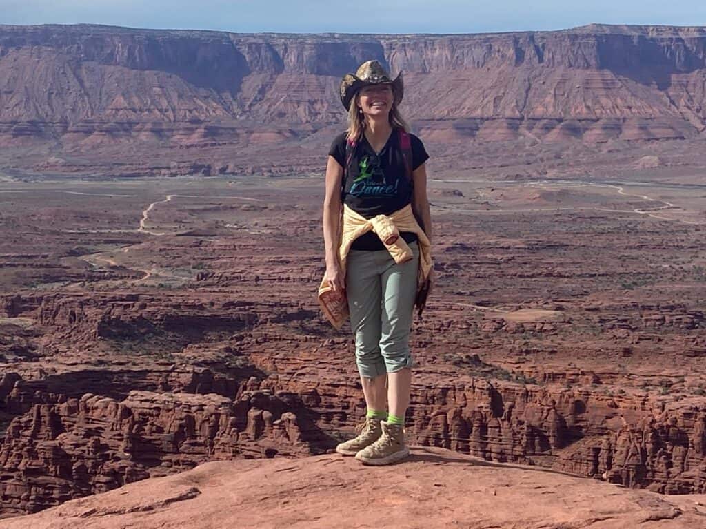 Hiker standing on rock ledge at Grand Canyon with scenic background.